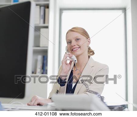 Portrait of confident businesswoman using computer and talking on telephone View Large Photo Image Stock Photo - Portrait of confident businesswoman using computer and talking on telephone. Fotosearch