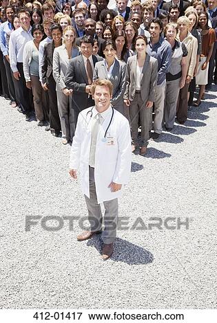 Portrait of confident doctor with business people in background View Large Photo Image Stock Photo - Portrait of confident doctor with business people in background. Fotosearch