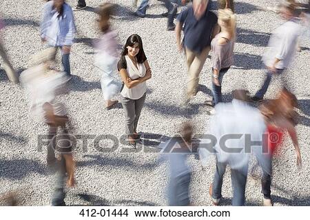 Portrait of confident woman standing among rushing crowd View Large Photo Image Picture - Portrait of confident woman standing among rushing crowd. Fotosearch