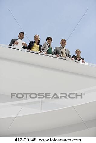 Portrait of smiling business people at railing of elevated walkway View Large Photo Image Stock Photo - Portrait of smiling business people at railing of elevated walkway. Fotosearch