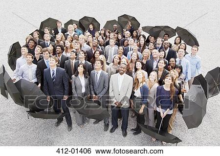 Stock Photograph - Portrait of smiling business people with umbrellas looking up. Fotosearch