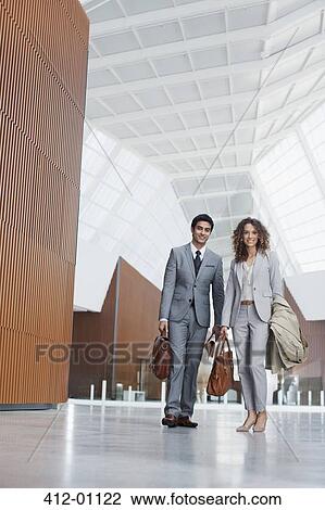 Portrait of smiling businessman and businesswoman in modern lobby View Large Photo Image Stock Image - Portrait of smiling businessman and businesswoman in modern lobby. Fotosearch