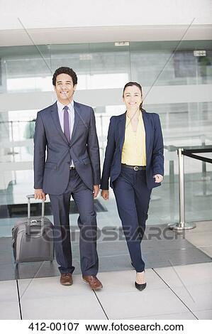 Portrait of smiling businessman and businesswoman with suitcase at airport View Large Photo Image Stock Photo - Portrait of smiling businessman and businesswoman with suitcase at airport. Fotosearch