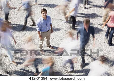 Portrait of smiling businessman surrounded by people rushing by View Large Photo Image Picture - Portrait of smiling businessman surrounded by people rushing by. Fotosearch