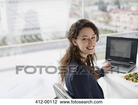 Portrait of smiling businesswoman using laptop and eating lunch View Large Photo Image Stock Image - Portrait of smiling businesswoman using laptop and eating lunch. Fotosearch