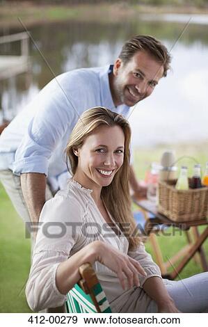 Portrait of smiling couple enjoying picnic at lakeside View Large Photo Image Stock Photo - Portrait of smiling couple enjoying picnic at lakeside. Fotosearch