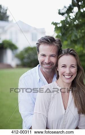 Portrait of smiling couple in yard with house in background View Large Photo Image Stock Image - Portrait of smiling couple in yard with house in background. Fotosearch