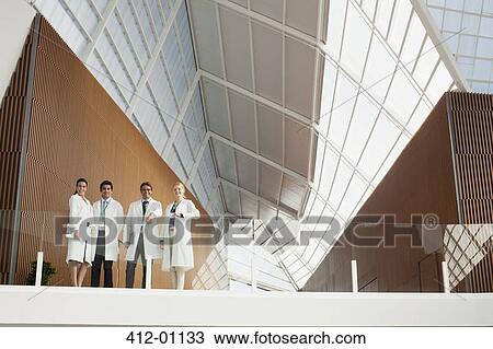 Portrait of smiling doctors at glass railing of balcony in modern building View Large Photo Image Stock Image - Portrait of smiling doctors at glass railing of balcony in modern building. Fotosearch