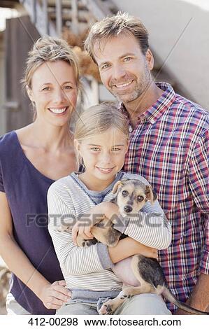 Portrait of smiling family holding puppy View Large Photo Image Stock Photo - Portrait of smiling family holding puppy. Fotosearch