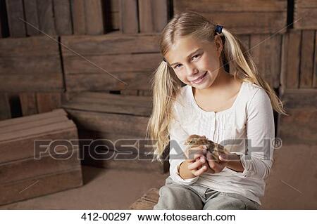 Portrait of smiling girl holding chick in barn View Large Photo Image Stock Photo - Portrait of smiling girl holding chick in barn. Fotosearch