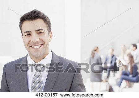 Portrait of smiling man with co-workers in background View Large Photo Image Stock Photo - Portrait of smiling man with co-workers in background. Fotosearch