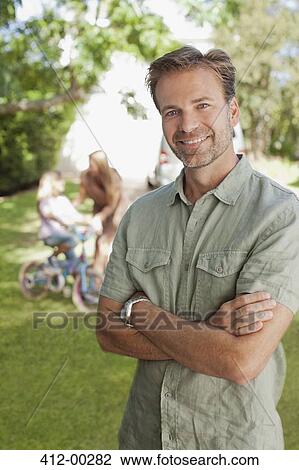 Stock Image - Portrait of smiling man with family in background. Fotosearch