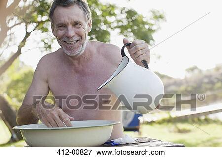 Portrait of smiling man with pitcher washing face in basin at lakeside View Large Photo Image Stock Photo - Portrait of smiling man with pitcher washing face in basin at lakeside. Fotosearch