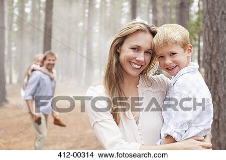 Portrait of smiling mother holding son in woods View Large Photo Image Picture - Portrait of smiling mother holding son in woods. Fotosearch
