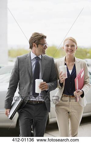 Smiling businessman and businesswoman walking with coffee cups View Large Photo Image Stock Photograph - Smiling businessman and businesswoman walking with coffee cups. Fotosearch