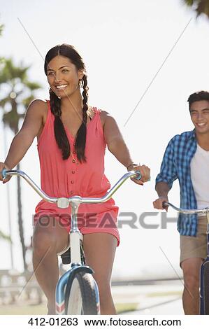 Stock Image - Smiling couple riding bicycles together. Fotosearch