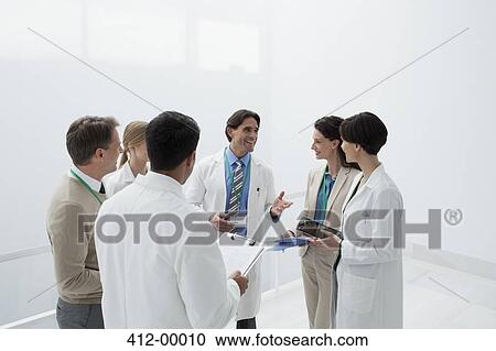 Stock Image - Smiling doctors discussing medical charts. Fotosearch