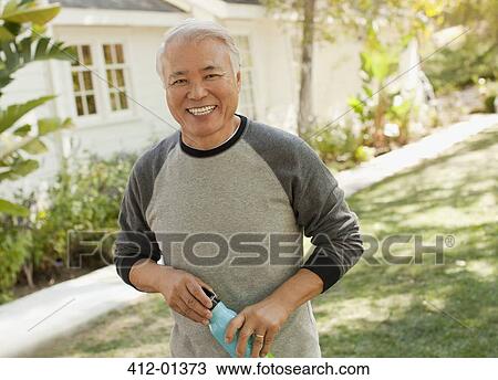 Stock Image - Smiling older man carrying water bottle. Fotosearch
