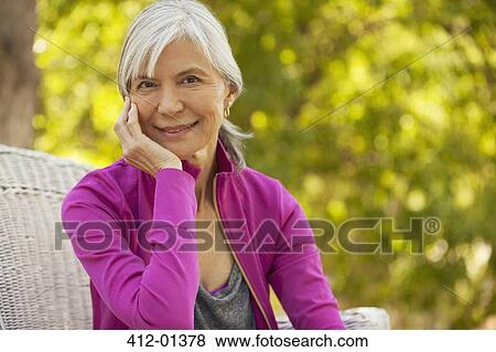 Smiling older woman sitting outdoors View Large Photo Image Stock Photo - Smiling older woman sitting outdoors. Fotosearch