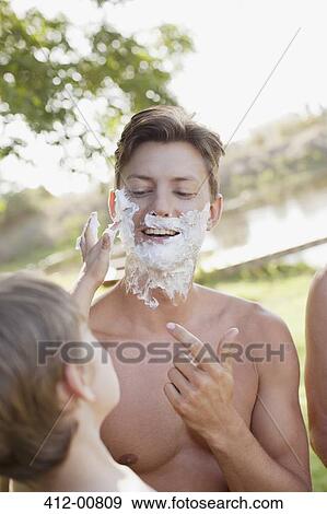 Son helping father apply shaving cream to face at lakeside View Large Photo Image Stock Photo - Son helping father apply shaving cream to face at lakeside. Fotosearch