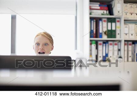 Surprised businesswoman reading e-mail at computer in office View Large Photo Image Stock Photo - Surprised businesswoman reading e-mail at computer in office. Fotosearch