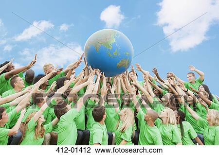 Team in green t-shirts lifting globe overhead View Large Photo Image Stock Image - Team in green t-shirts lifting globe overhead. Fotosearch