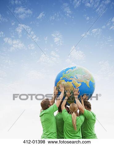 Team in green t-shirts lifting globe overhead View Large Photo Image Stock Photo - Team in green t-shirts lifting globe overhead. Fotosearch