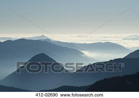 Stock Image - Aerial view of mountaintops over clouds. Fotosearch
