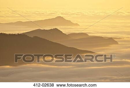 Aerial view of mountaintops over clouds at sunset View Large Photo Image Stock Photo - Aerial view of mountaintops over clouds at sunset. Fotosearch