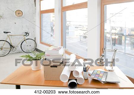 Stock Image - Blueprints and papers on desk in office. Fotosearch