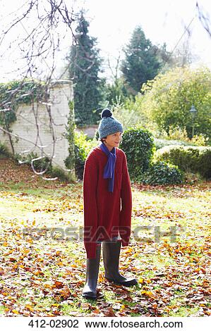 Stock Image - Boy wearing father's sweater and boots outdoors. Fotosearch