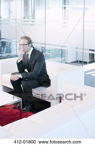 Business man sitting on sofa in office lobby View Large Photo Image Stock Image - Business man sitting on sofa in office lobby. Fotosearch