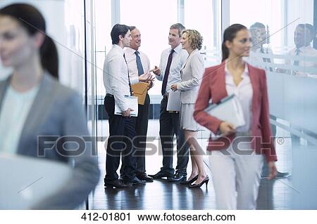 Stock Image - Business people talking in office hallway. Fotosearch
