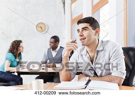 Businessman sitting at desk in office View Large Photo Image Stock Photo - Businessman sitting at desk in office. Fotosearch