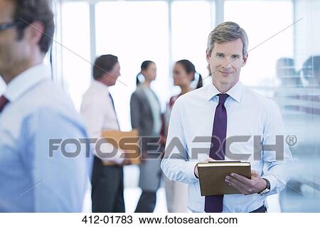 Businessman smiling in office hallway View Large Photo Image Stock Image - Businessman smiling in office hallway. Fotosearch