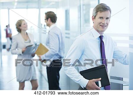 Businessman smiling in office hallway View Large Photo Image Stock Image - Businessman smiling in office hallway. Fotosearch