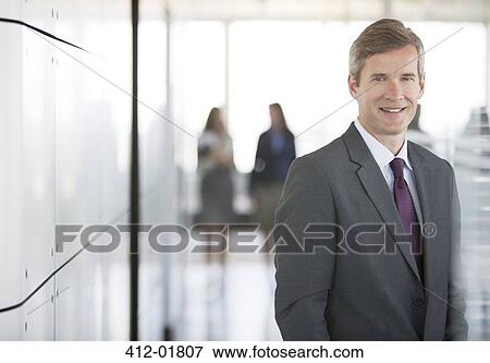 Stock Photo - Businessman smiling in office hallway. Fotosearch