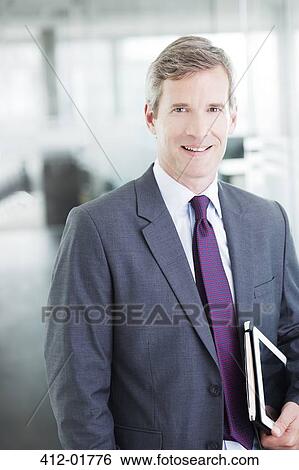 Businessman smiling in office hallway View Large Photo Image Stock Photograph - Businessman smiling in office hallway. Fotosearch