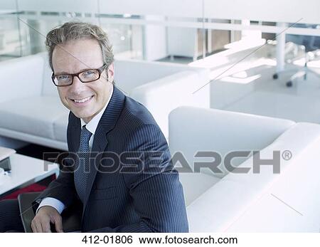 Businessman smiling in office lobby View Large Photo Image Stock Photograph - Businessman smiling in office lobby. Fotosearch