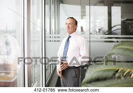 Stock Photography - Businessman standing at office window. Fotosearch