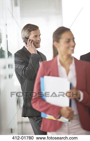 Businessman talking on cell phone in office hallway View Large Photo Image Stock Image - Businessman talking on cell phone in office hallway. Fotosearch