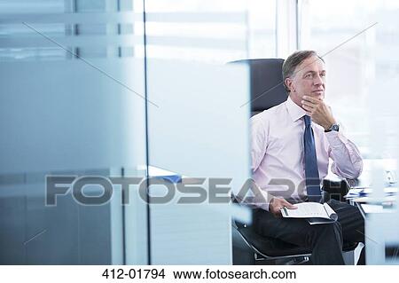 Picture - Businessman thinking at desk. Fotosearch