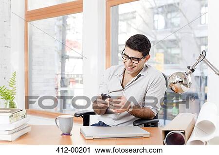 Businessman using cell phone in office View Large Photo Image Stock Image - Businessman using cell phone in office. Fotosearch