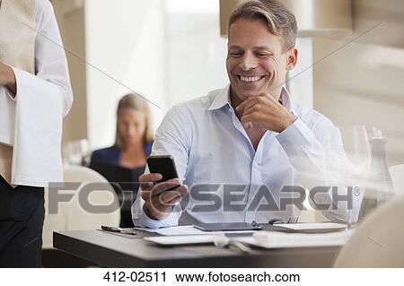 Businessman using cell phone in restaurant View Large Photo Image Stock Image - Businessman using cell phone in restaurant. Fotosearch