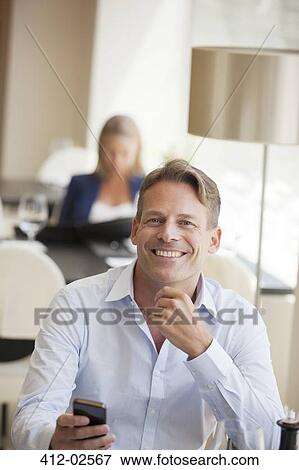 Businessman using cell phone in restaurant View Large Photo Image Stock Photo - Businessman using cell phone in restaurant. Fotosearch