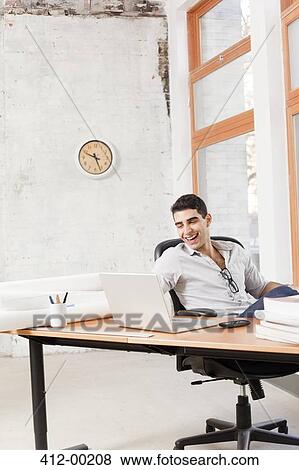 Businessman working at laptop in office View Large Photo Image Stock Photo - Businessman working at laptop in office. Fotosearch