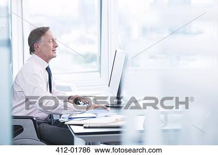 Stock Photograph - Businessman working on computer at desk. Fotosearch
