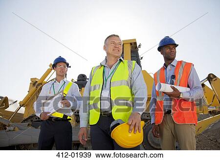 Businessmen in hard hats standing on site View Large Photo Image Stock Photo - Businessmen in hard hats standing on site. Fotosearch