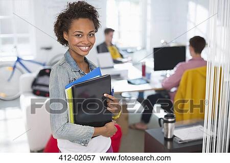 Stock Photo - Businesswoman carrying laptop in office. Fotosearch