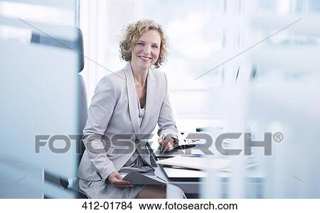 Businesswoman smiling at desk View Large Photo Image Picture - Businesswoman smiling at desk. Fotosearch
